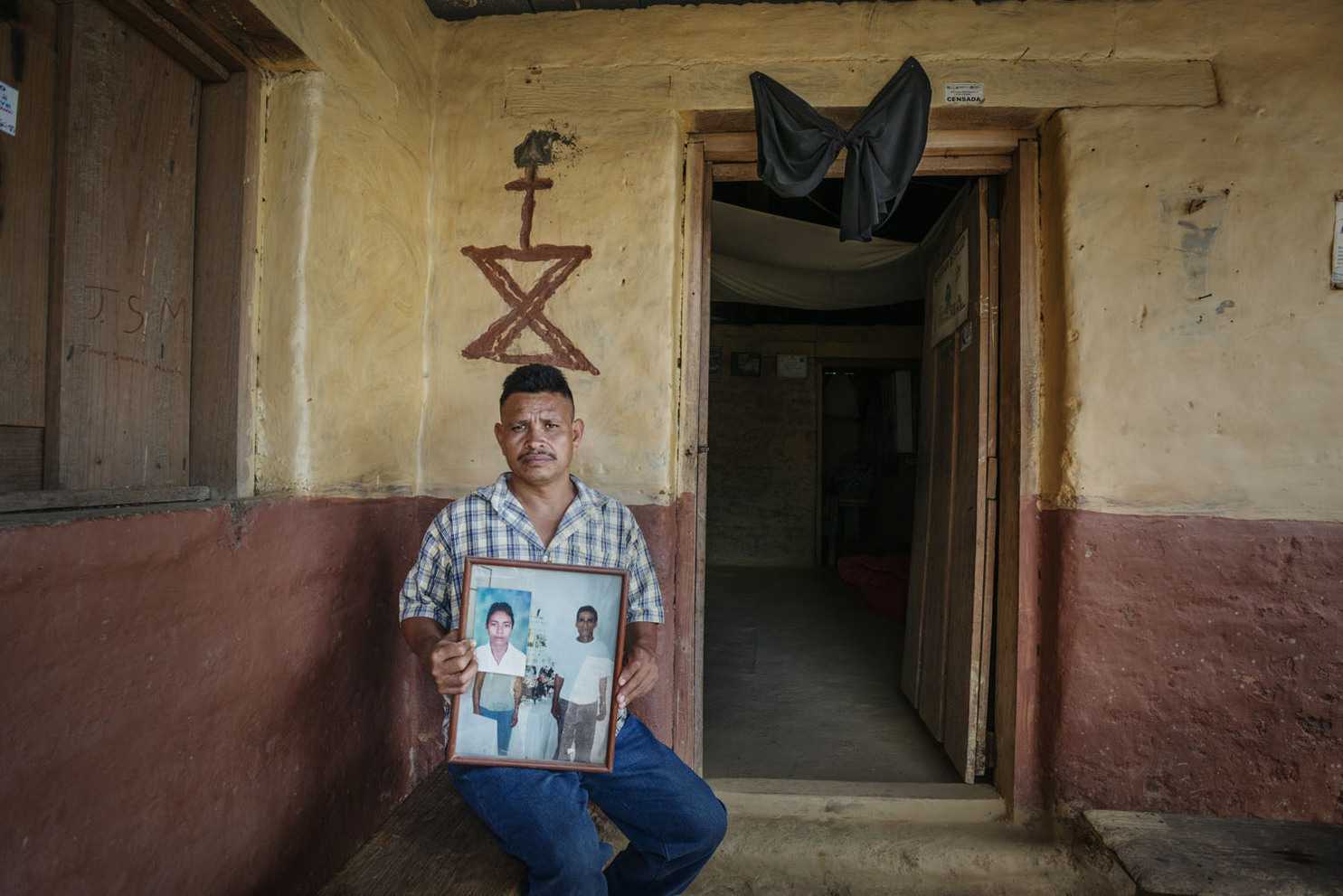 Ramón Santiago Matute Ávila mostrando fotografias de su padre y hermano